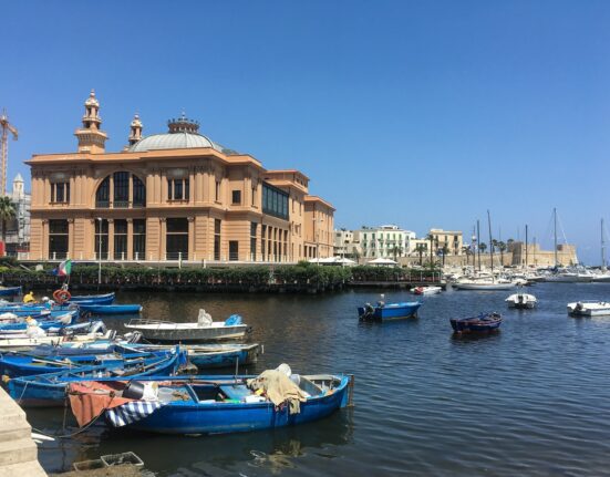blue and white boats on sea viewing building