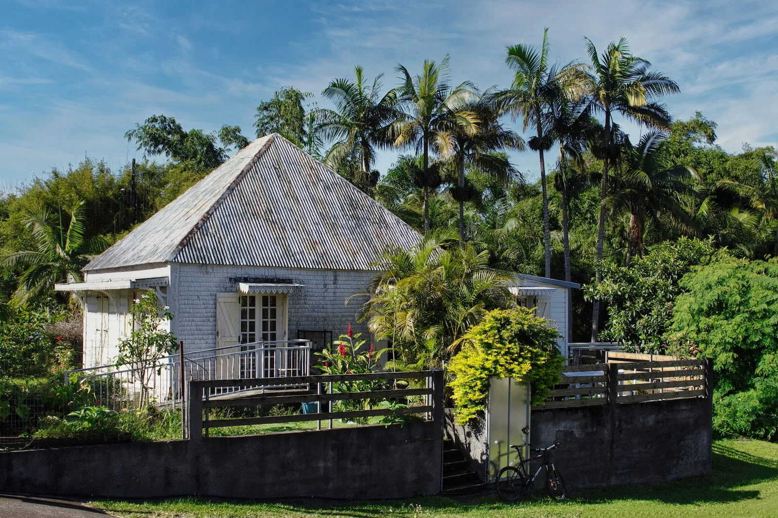 a small house with a fence and trees in the background