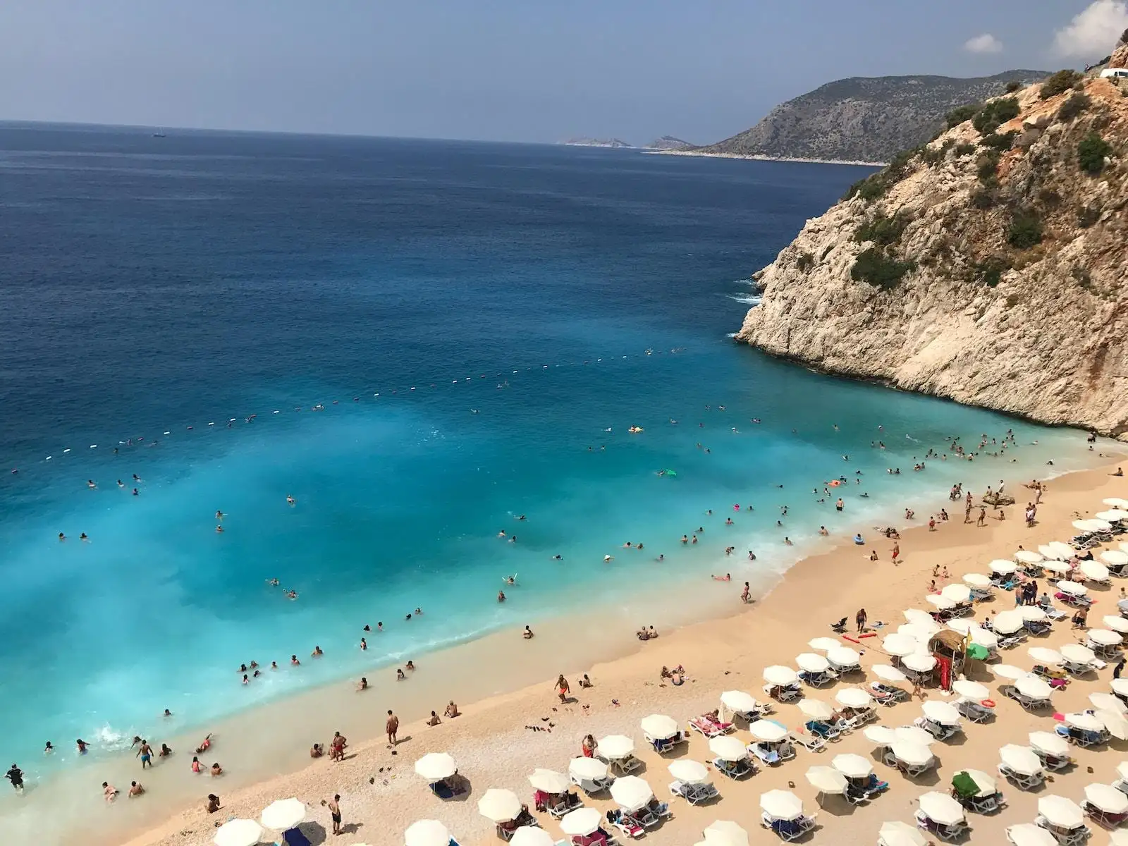 Photo by Serdar Dincer high angle photo of people gathering on seashore near mountain cliff
