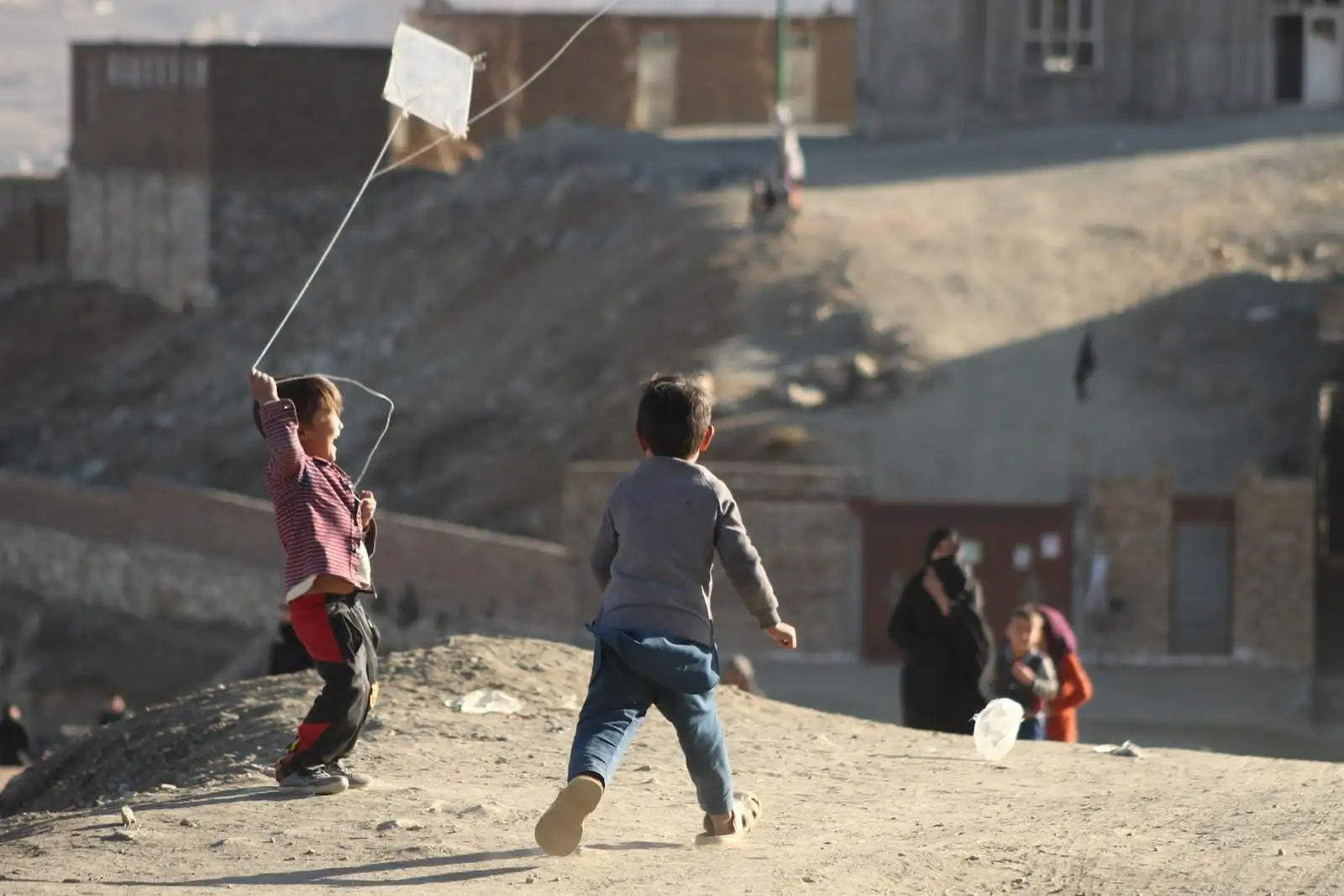 Photo by Farid Ershad a couple of kids flying a kite on top of a hill