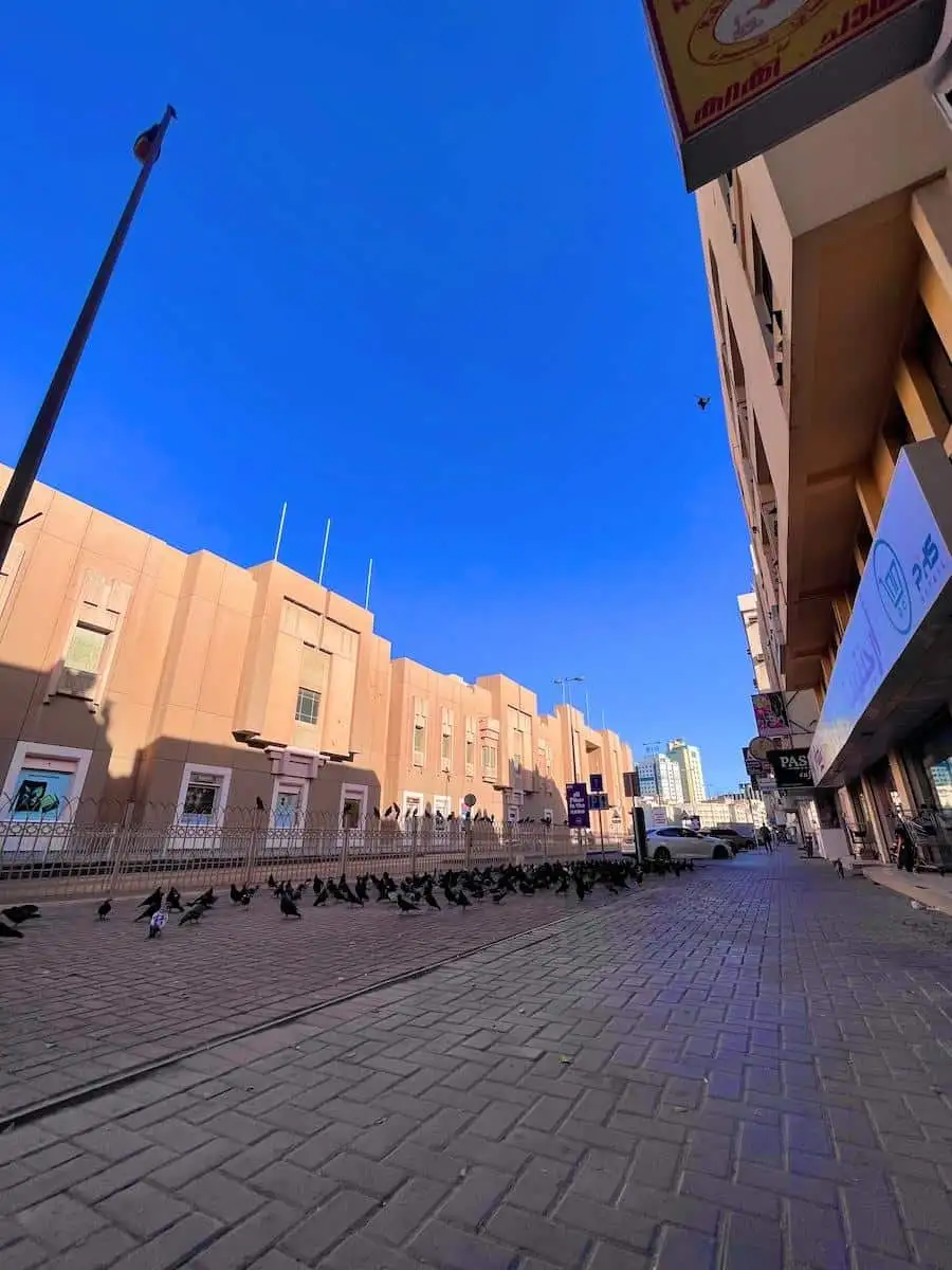 Photo by AHMAD YAHYA a brick road with a crowd of people on it and buildings in the background