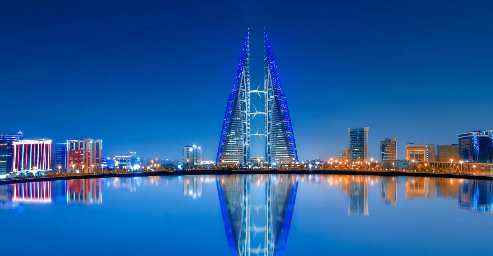 Blue and Purple Lighted Tower Near Body of Water during Night Time