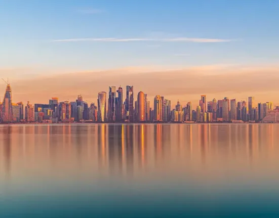 Scenic cityscape of modern coastal megapolis under sunset sky