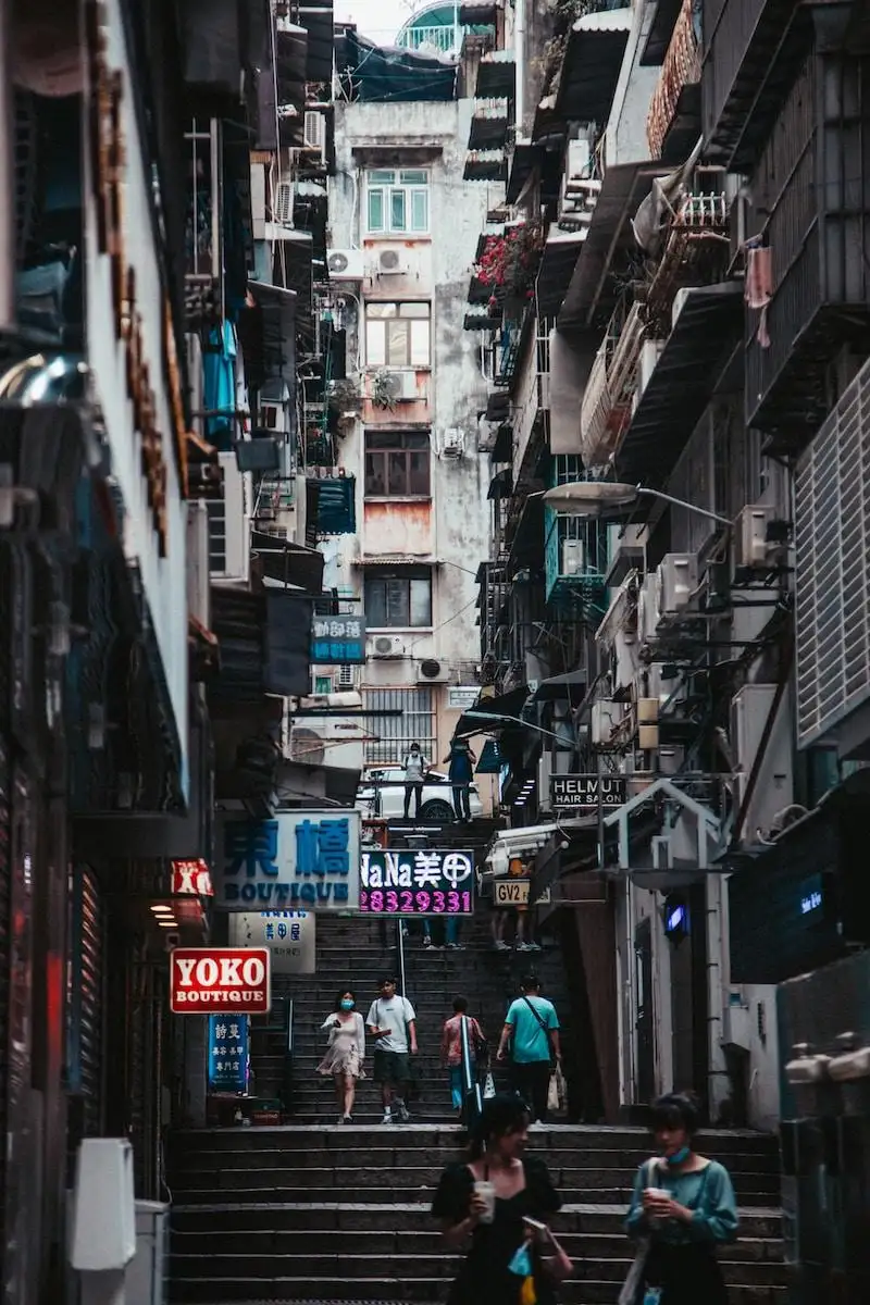 Photo by Roland Kwok a group of people walking down a street next to tall buildings