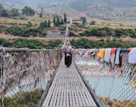 person walking on bridge with clothes hanging