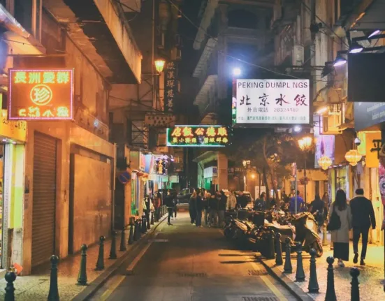 a city street at night with people walking on the sidewalk