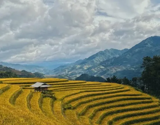 green grass field near mountains under white clouds during daytime