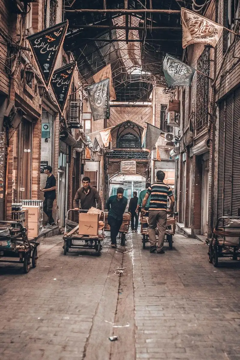 Photo by Omid Armin a group of people walking down a street next to tall buildings