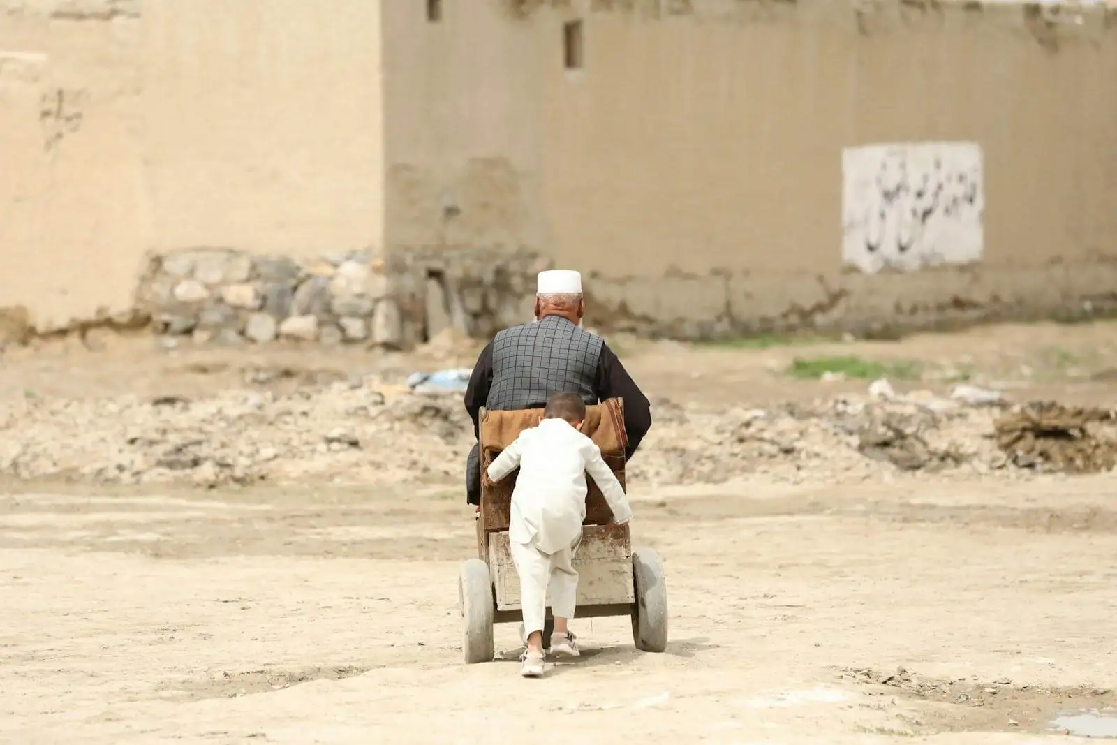 Photo by Sohaib Ghyasi man in white long sleeve shirt and white pants sitting on brown sand during daytime