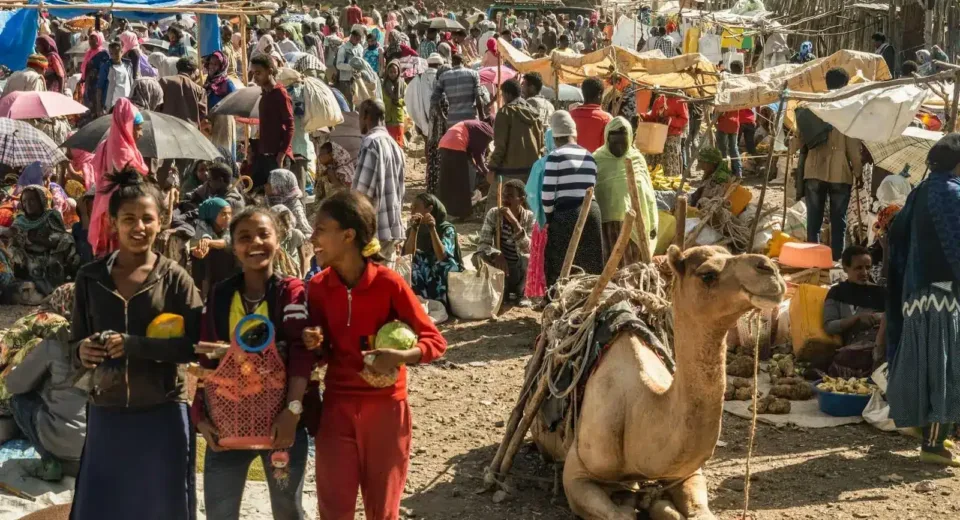 a group of people standing in a crowded area with camels and tents