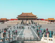a group of people walking in a courtyard with Forbidden City in the background