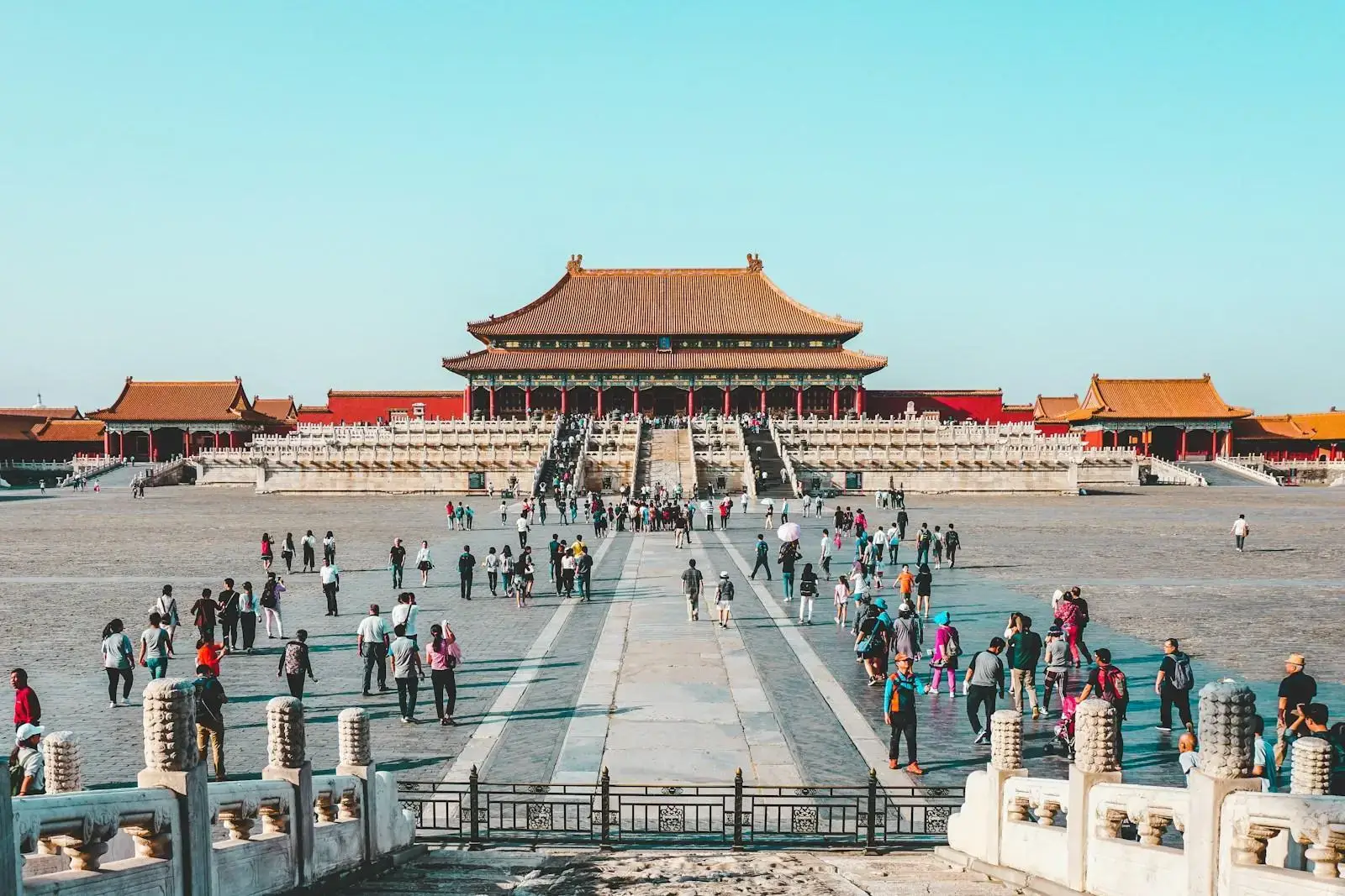 a group of people walking in a courtyard with Forbidden City in the background